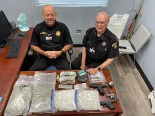 Towns County Sheriff Ken Henderson and Chief Deputy Gene Moss display drugs, guns and cash seized in the June 17 bust. Henderson praised the Sheriff’s Drug Investigative unit and deputies who he said put in long hours on these investigations. 
