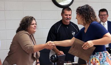 (Jared Putnam • Clay County Progress) From left, Clay County Board of Education member Kelly Crawford shakes hands with Emily Mull, Clay County Schools' Teacher of the Year, while board chairperson Jason Shook and Superintendent Dale Cole look on during the June meeting on Monday in Hayesville.